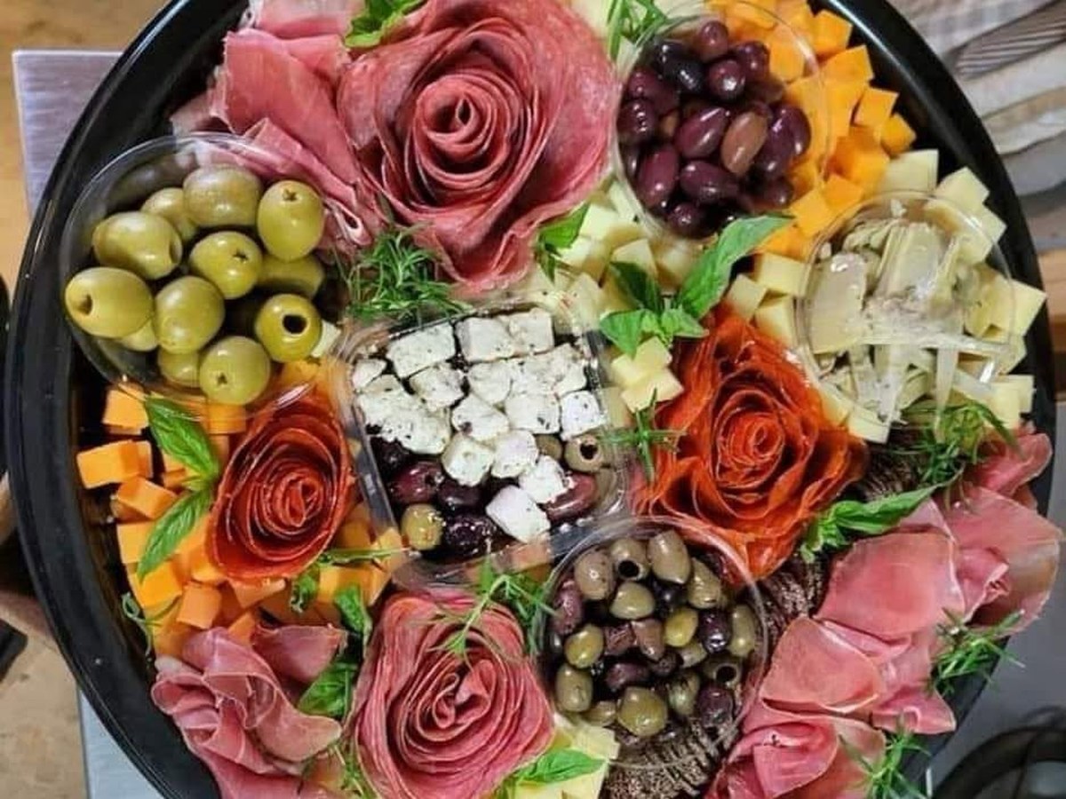 A full Italian catering spread with antipasto, hot trays, and bread